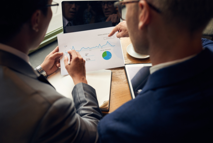 Two people discuss financial charts and graphs